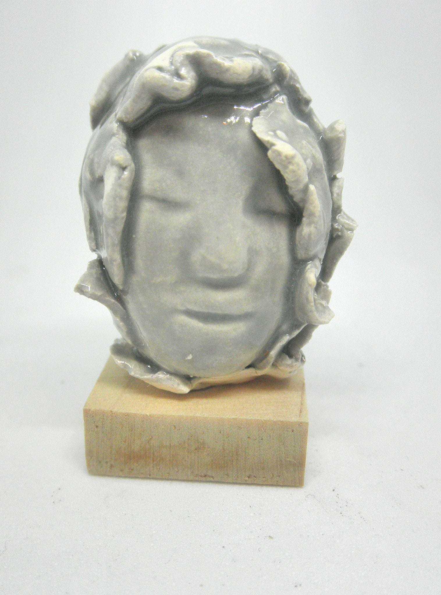 Miniature ceramic collector sculpture of a face surrounded by leaves - grey