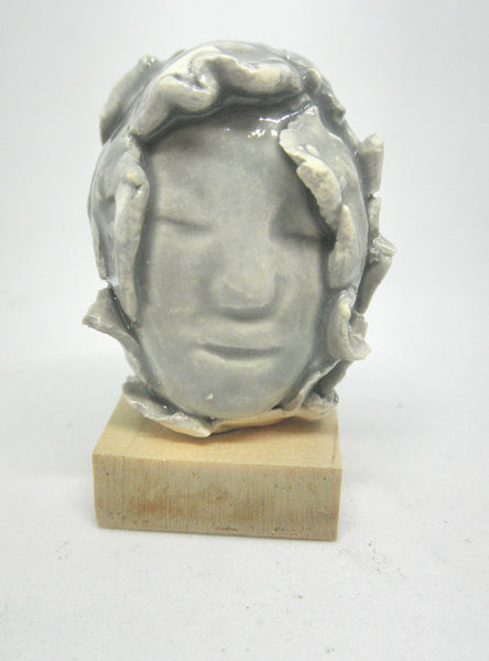 Miniature ceramic collector sculpture of a face surrounded by leaves - grey