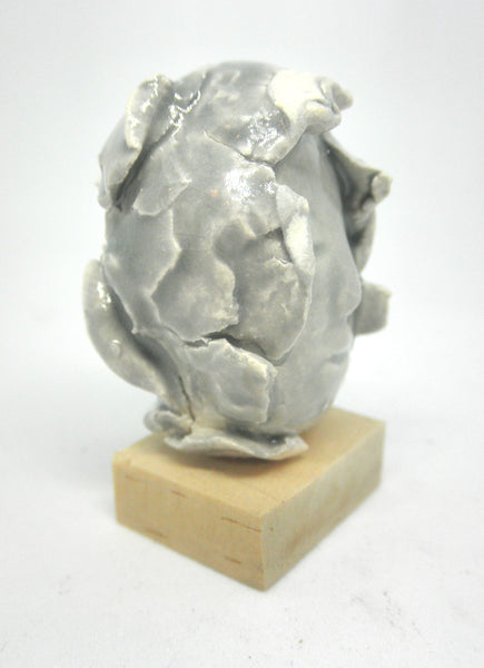 Miniature ceramic collector sculpture of a face surrounded by leaves - grey