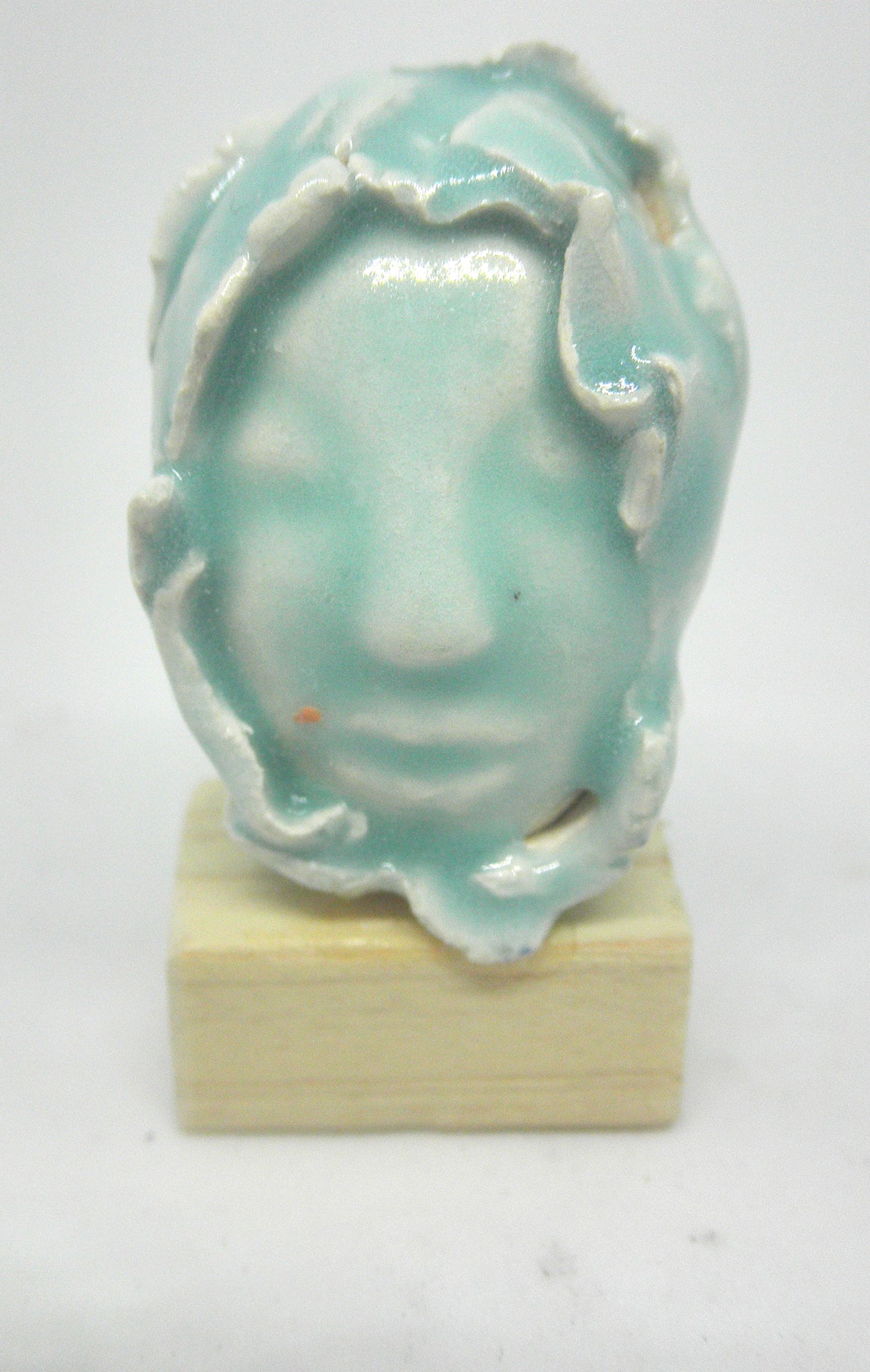 Miniature ceramic collector sculpture of a face surrounded by leaves - light green