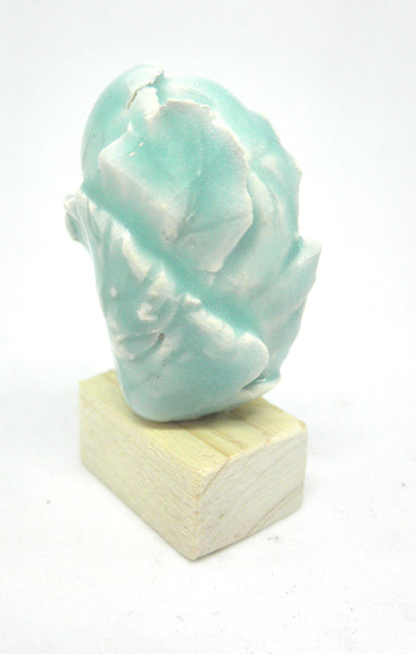 Miniature ceramic collector sculpture of a face surrounded by leaves - light green