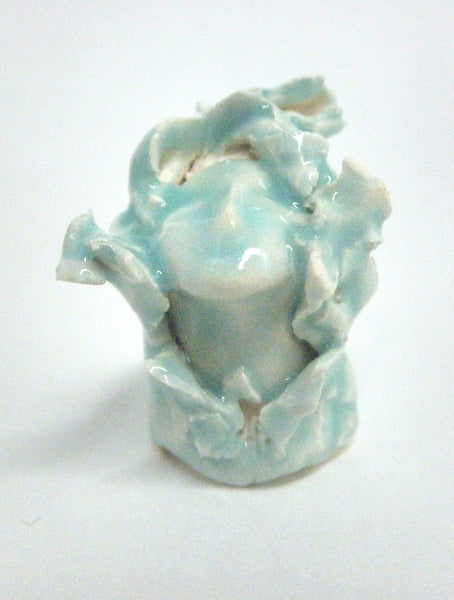 Miniature ceramic sculpture of a small face surrounded by leaves - light green