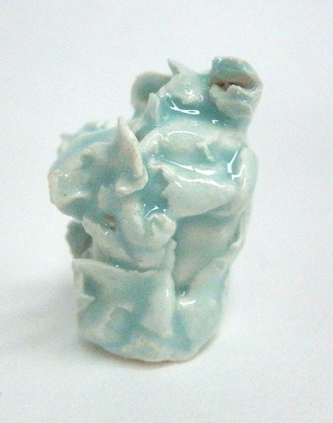 Miniature ceramic sculpture of a small face surrounded by leaves - light green