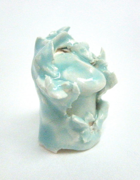 Miniature ceramic sculpture of a small face surrounded by leaves - light green