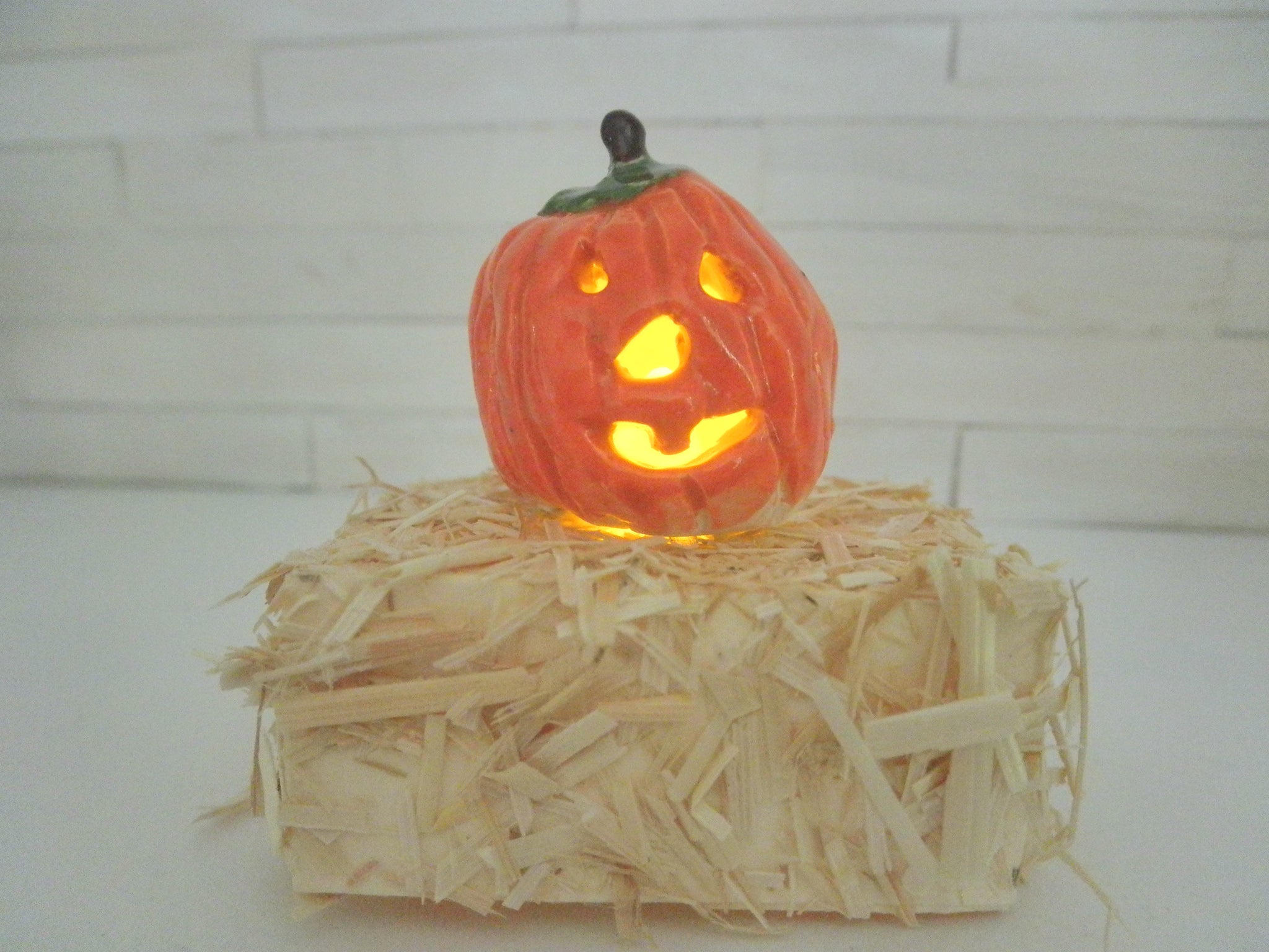Miniature Halloween carved Pumpkin lit on a bail of hay #1