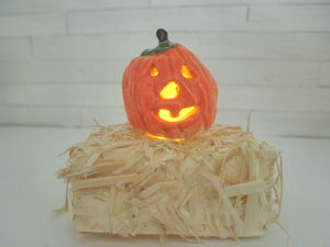 Miniature Halloween carved Pumpkin lit on a bail of hay #1